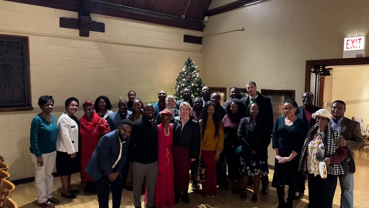 Members of Tumaini Swahili Chapel standing together for a group photo in the sanctuary, beside a Christmas tree