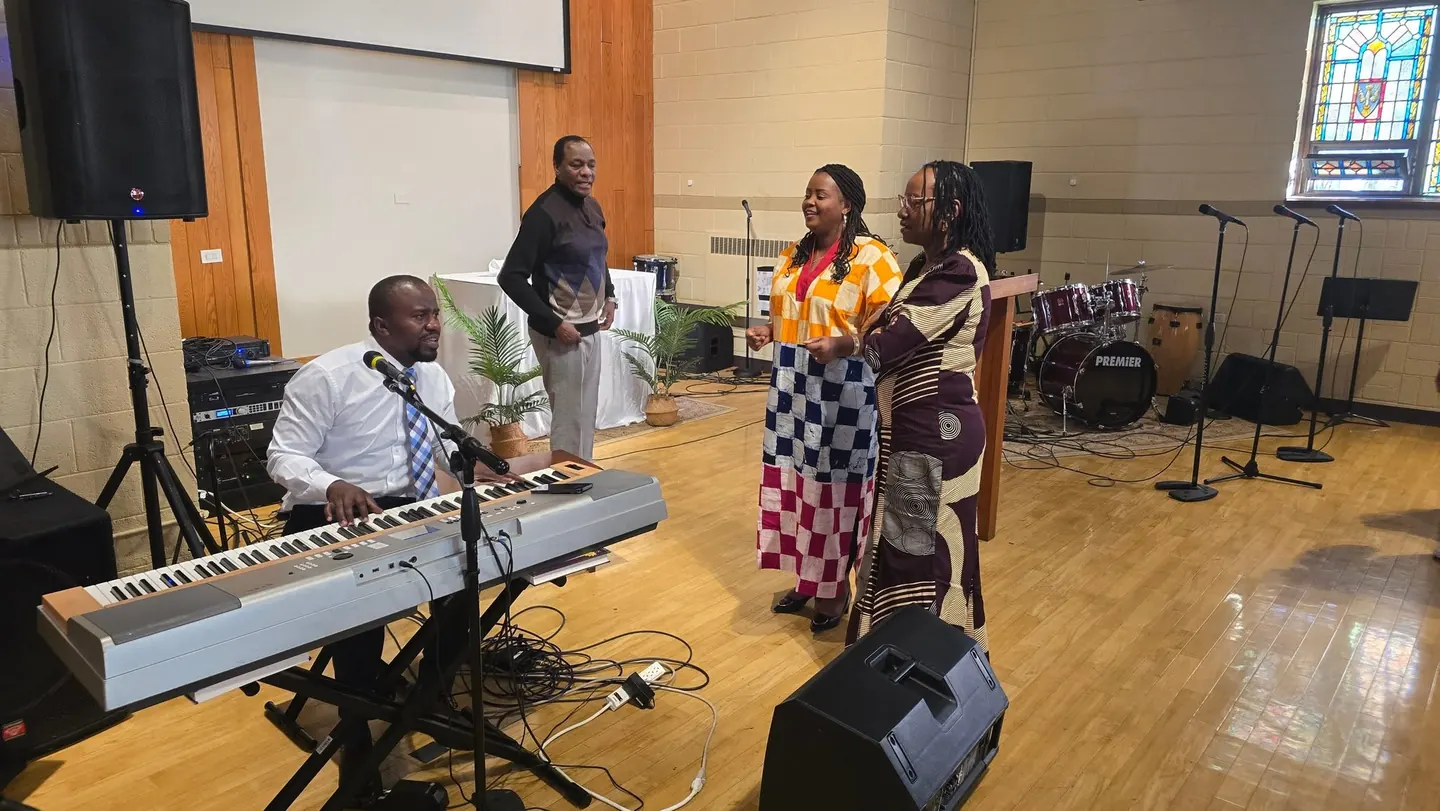 Two women singers and a keyboardist leading worship at the front of the sanctuary, with a drum kit behind them